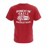 Back of red t-shirt featuring white weathered graphic of a crawfish tray, beer bottle, and the text Pinchan' Tails Drinkin' Beer.